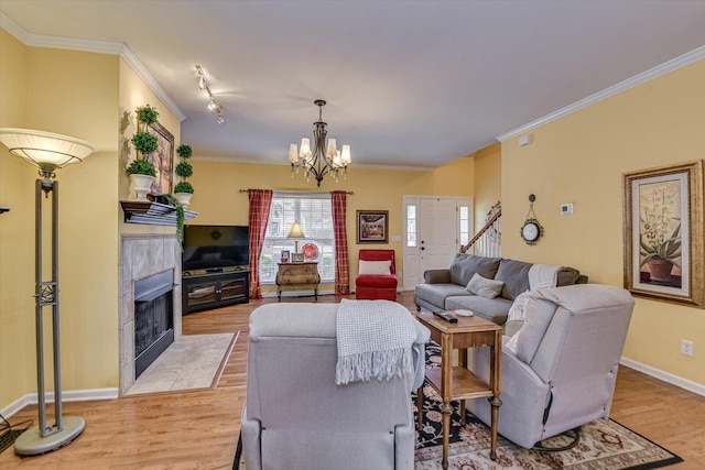 living area with light wood-style floors, baseboards, ornamental molding, and a tiled fireplace