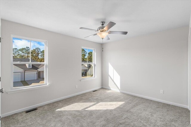 carpeted spare room with ceiling fan and plenty of natural light