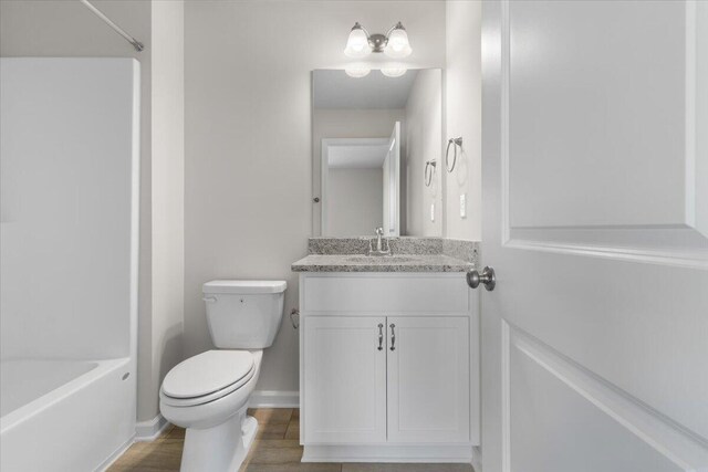 full bathroom with hardwood / wood-style flooring, vanity, bathtub / shower combination, and toilet