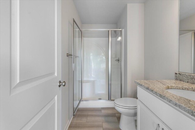 bathroom with a shower with door, vanity, and toilet