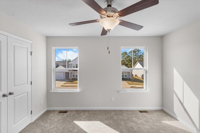 carpeted spare room featuring ceiling fan