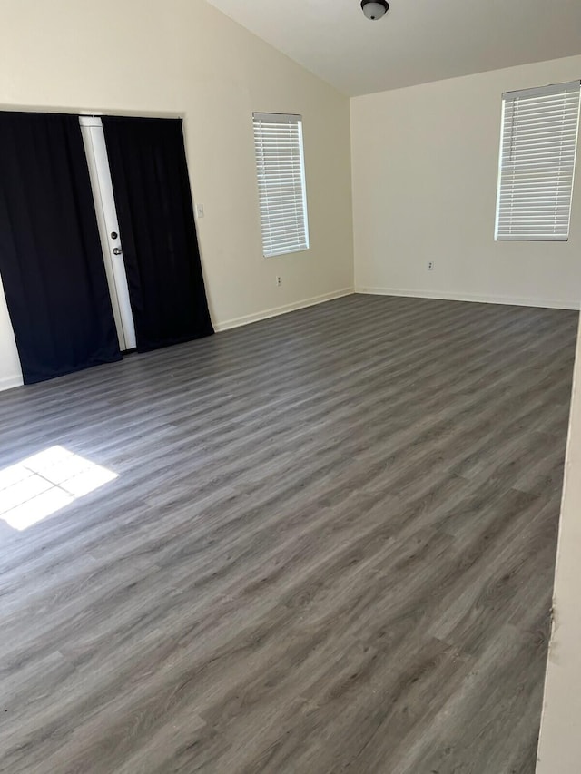 unfurnished room featuring dark wood-type flooring and lofted ceiling