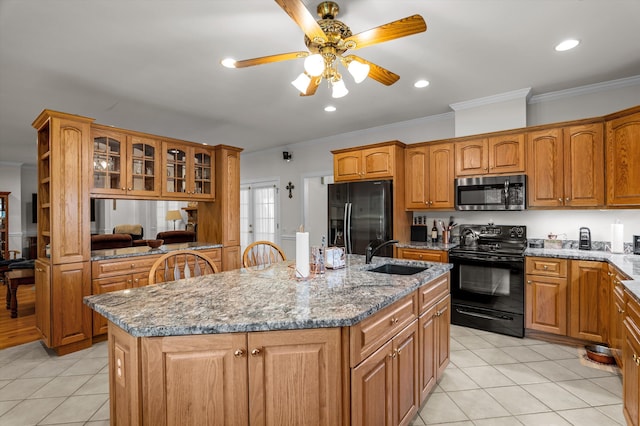 kitchen featuring black appliances, a sink, crown molding, an island with sink, and light tile patterned flooring