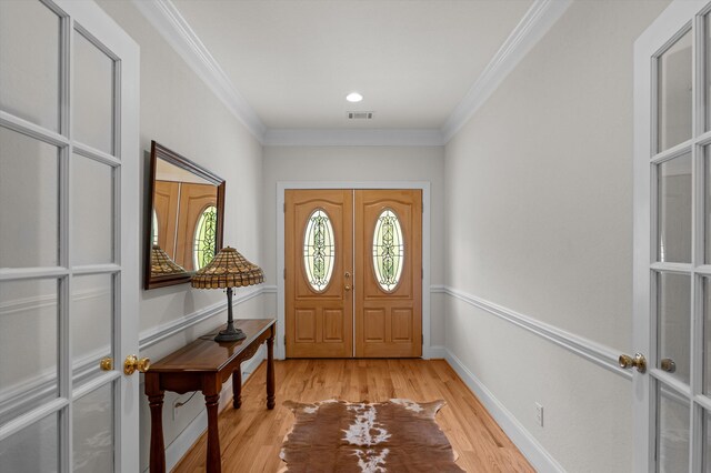 entryway with crown molding, light wood finished floors, and baseboards