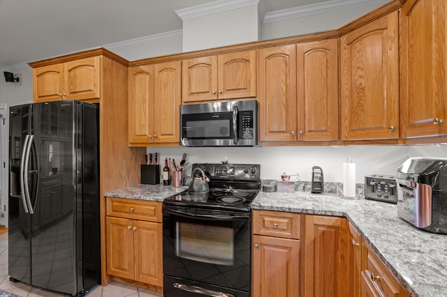kitchen with black appliances, ornamental molding, light tile patterned floors, light stone countertops, and brown cabinets