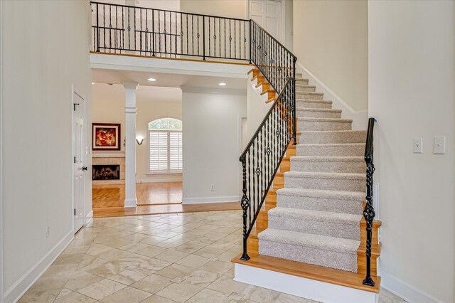 3954 Hammonds Fry, Evans, GA 30809 - stairs with marble look tile flooring, ornate columns, a fireplace, and a towering ceiling