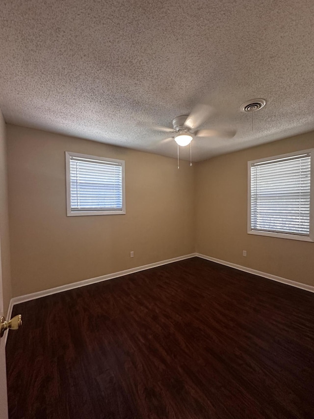 empty room featuring dark hardwood / wood-style floors, ceiling fan, and a textured ceiling