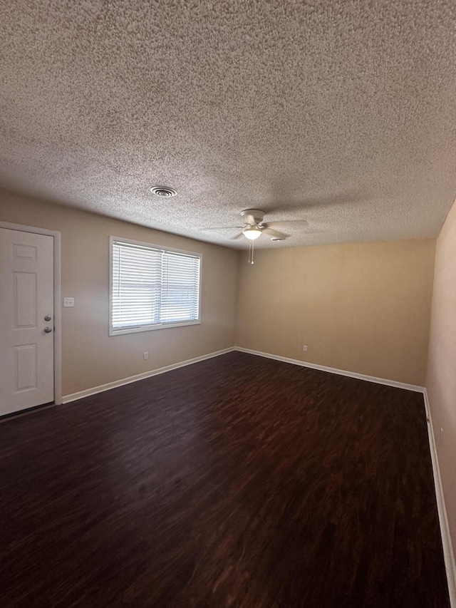 spare room featuring ceiling fan, dark hardwood / wood-style flooring, and a textured ceiling