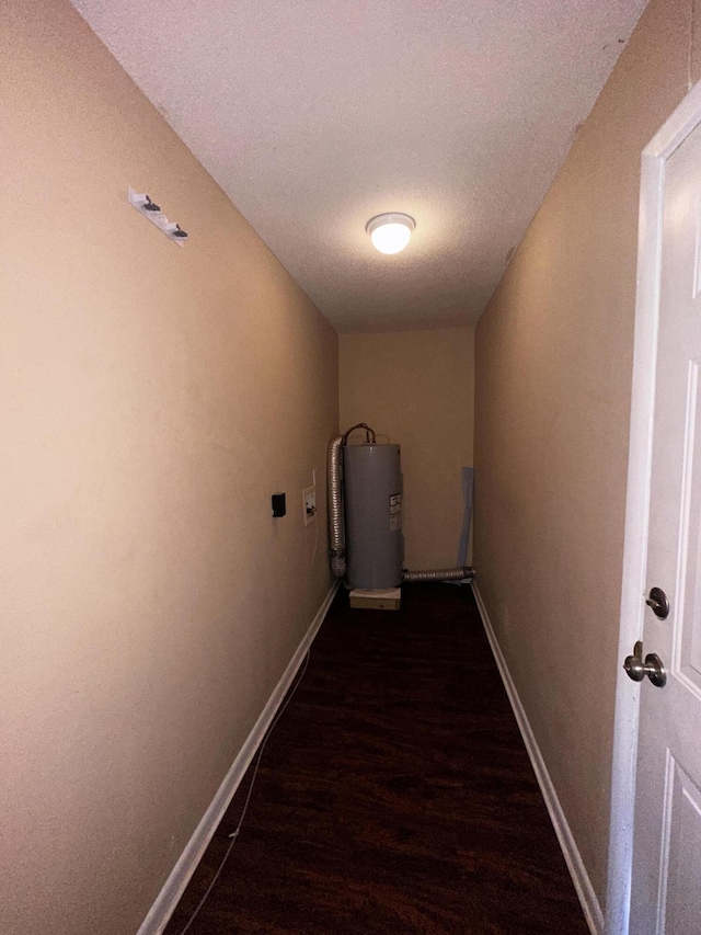 corridor with a textured ceiling, dark wood-type flooring, and water heater