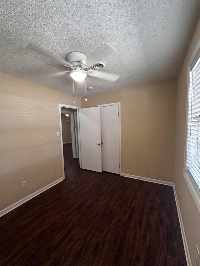 unfurnished bedroom with multiple windows, a closet, dark hardwood / wood-style floors, and ceiling fan