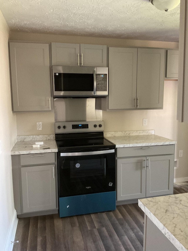 kitchen featuring stainless steel appliances, a textured ceiling, gray cabinetry, and dark wood-style floors