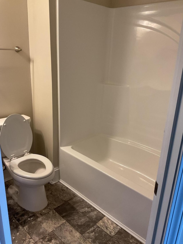 full bath featuring stone finish floor and toilet