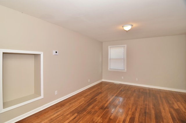 unfurnished room with baseboards and dark wood-type flooring