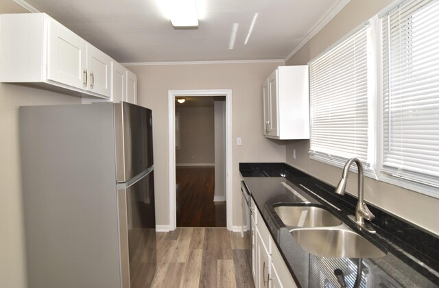 kitchen with light wood finished floors, a sink, freestanding refrigerator, white cabinetry, and ornamental molding