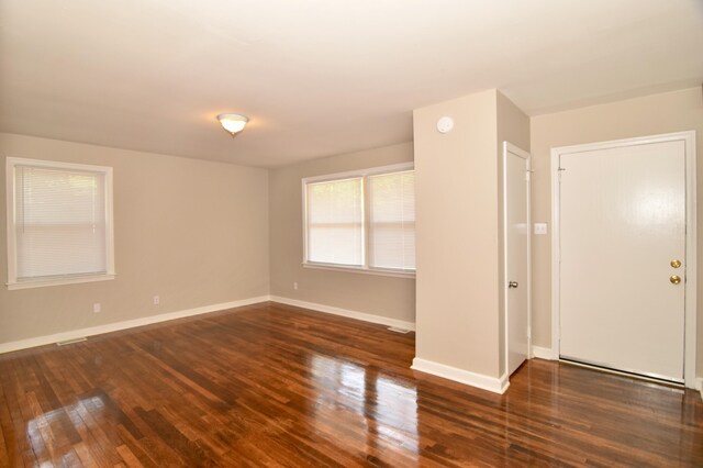 spare room featuring wood-type flooring and baseboards