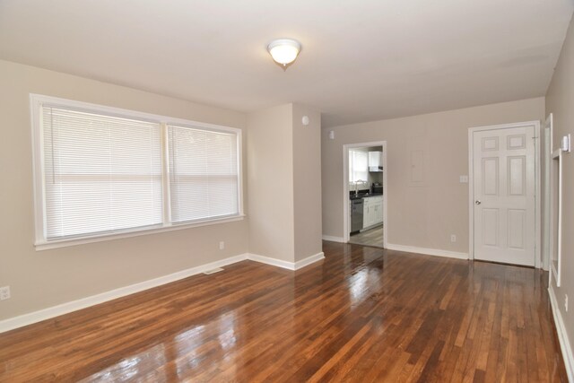 unfurnished room with visible vents, baseboards, and dark wood-style floors