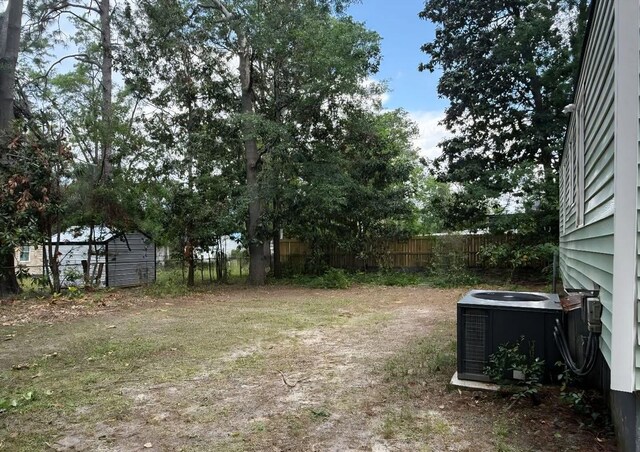view of yard with central AC and fence