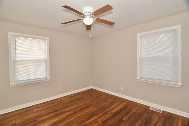 spare room featuring a ceiling fan, baseboards, dark wood-style flooring, and visible vents