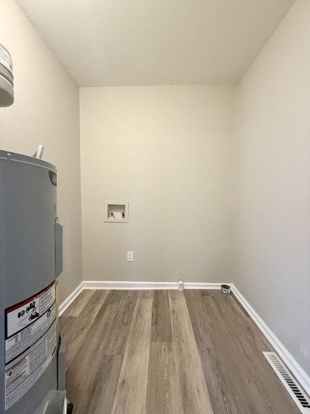 clothes washing area with wood finished floors, visible vents, laundry area, and electric water heater