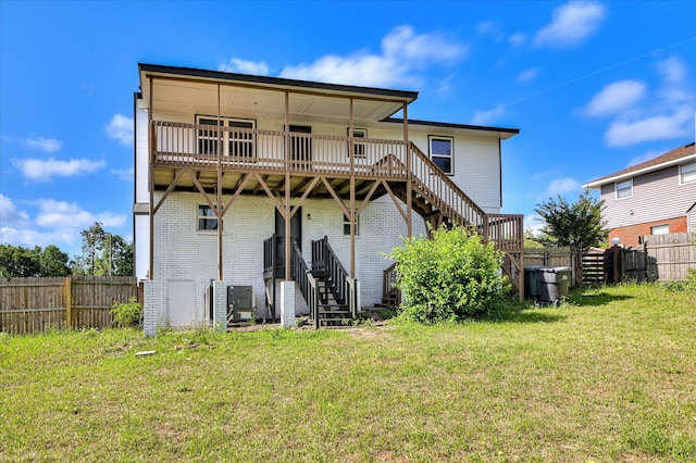 rear view of property with stairway, a lawn, a wooden deck, and a fenced backyard
