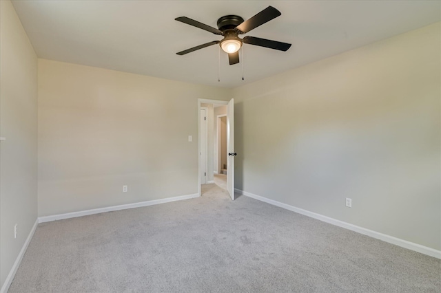 spare room featuring a ceiling fan, baseboards, and light carpet