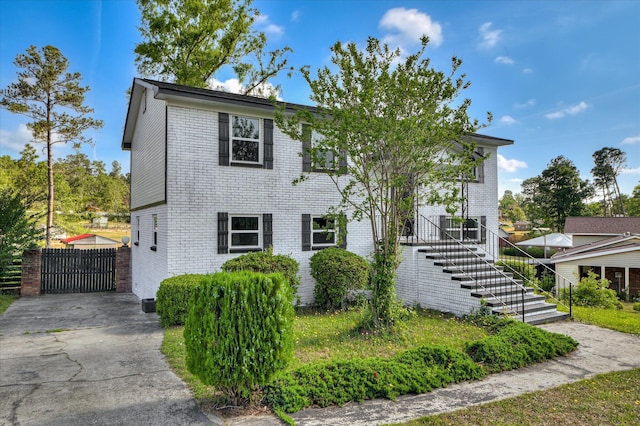 view of front of property with brick siding, fence, driveway, and stairway