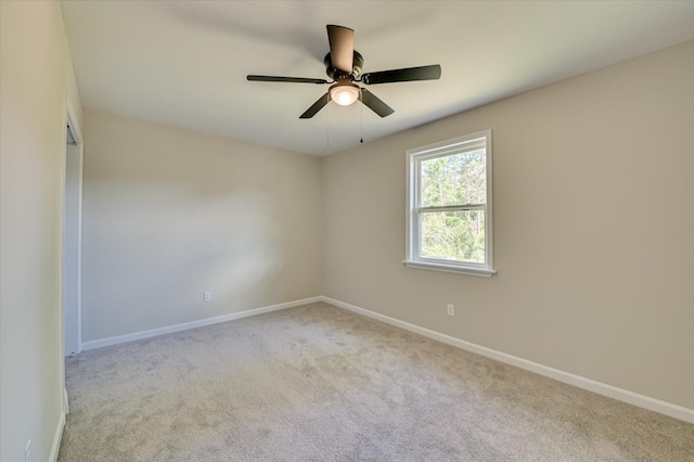 carpeted empty room with a ceiling fan and baseboards