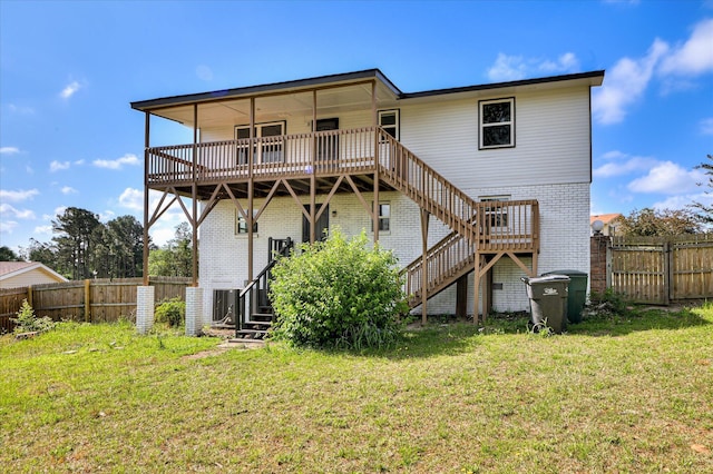 back of property featuring stairway, brick siding, a yard, and a fenced backyard