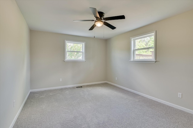 carpeted spare room featuring baseboards, a ceiling fan, and visible vents
