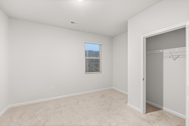 unfurnished bedroom featuring light colored carpet and a closet