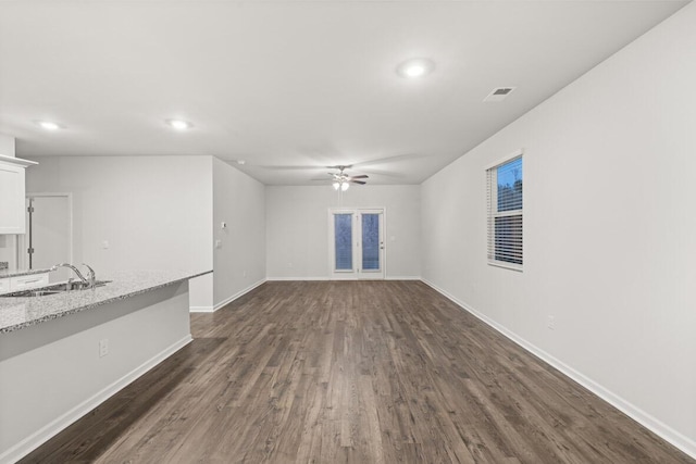 unfurnished living room with sink, ceiling fan, and dark wood-type flooring