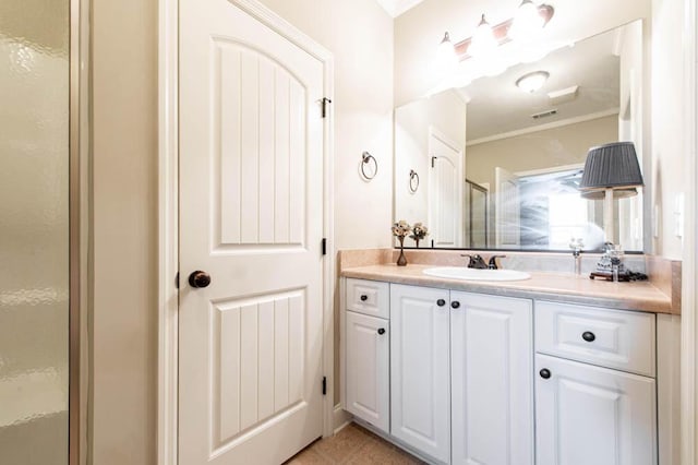 bathroom with a stall shower, visible vents, tile patterned floors, crown molding, and vanity