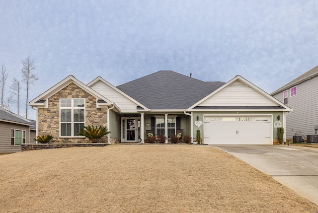 craftsman inspired home featuring concrete driveway, stone siding, an attached garage, and central air condition unit