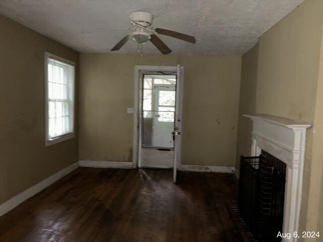 unfurnished living room with a wealth of natural light, a textured ceiling, dark hardwood / wood-style floors, and ceiling fan