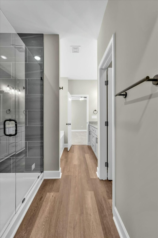 bathroom featuring wood finished floors, a stall shower, vanity, baseboards, and visible vents