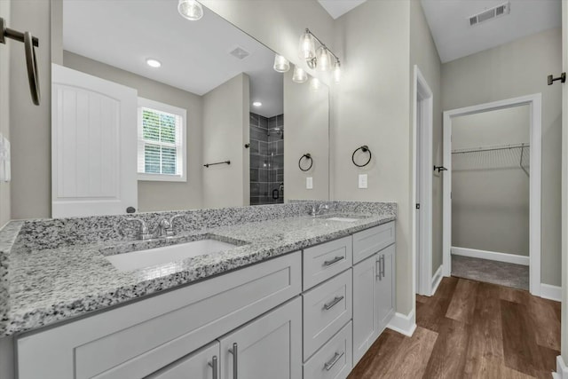 full bath featuring wood finished floors, visible vents, a sink, and a shower stall