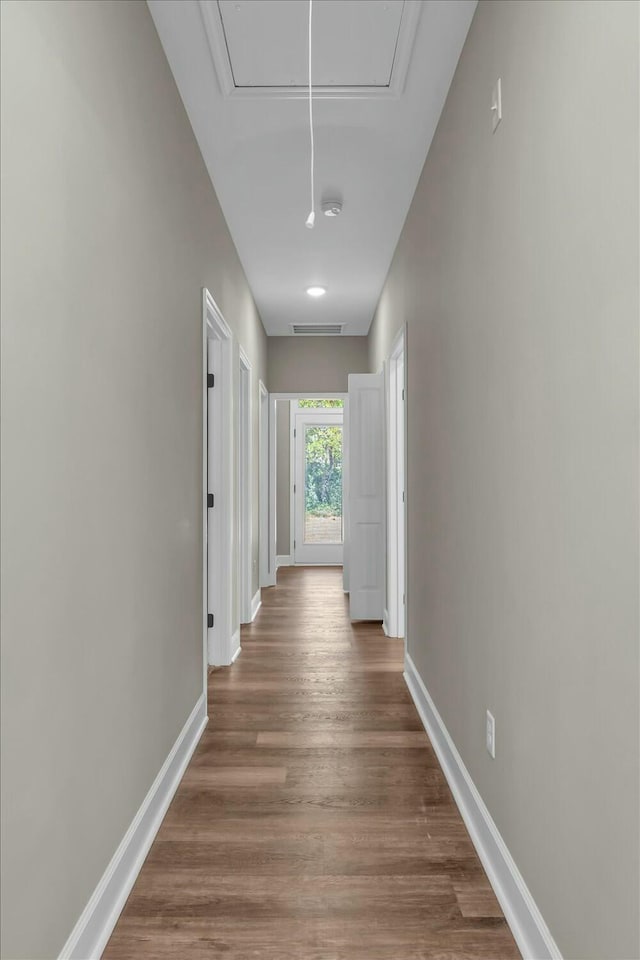 hall with attic access, wood finished floors, and baseboards