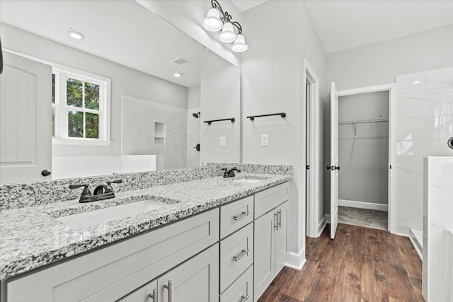 bathroom featuring a tile shower, wood-type flooring, and vanity