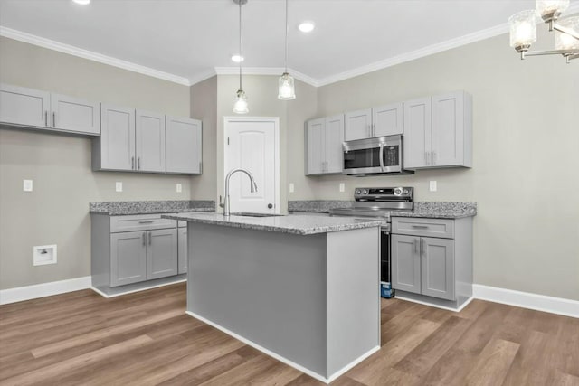 kitchen with ornamental molding, gray cabinetry, stainless steel appliances, and a sink