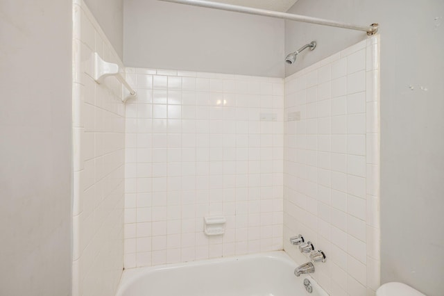 bathroom featuring tiled shower / bath combo and toilet