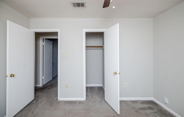 unfurnished bedroom featuring light carpet, ceiling fan, a closet, and a textured ceiling