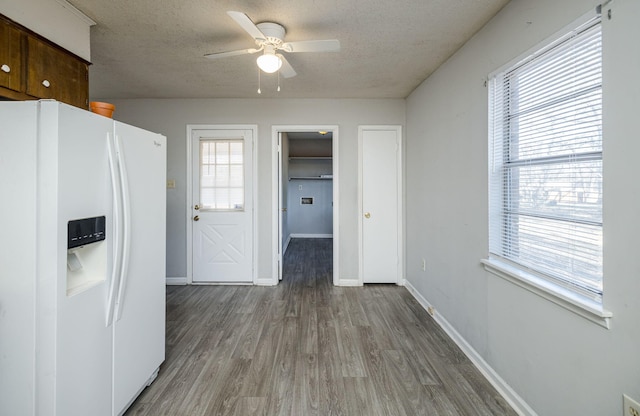 kitchen featuring a textured ceiling, ceiling fan, white refrigerator with ice dispenser, and hardwood / wood-style flooring