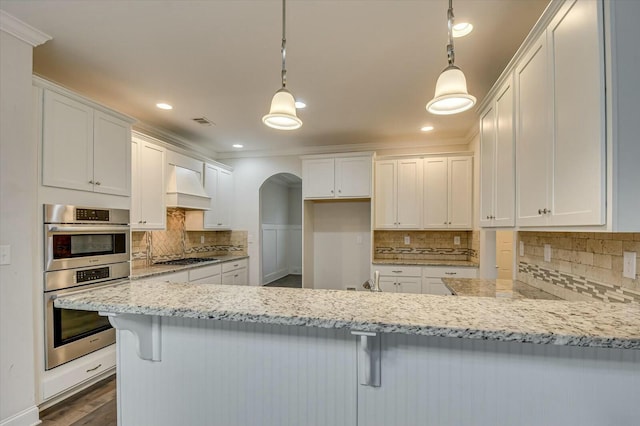 kitchen with hanging light fixtures, light stone countertops, white cabinets, and appliances with stainless steel finishes