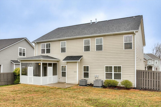 back of house with a sunroom, a lawn, and central air condition unit