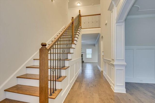 staircase with crown molding and wood-type flooring