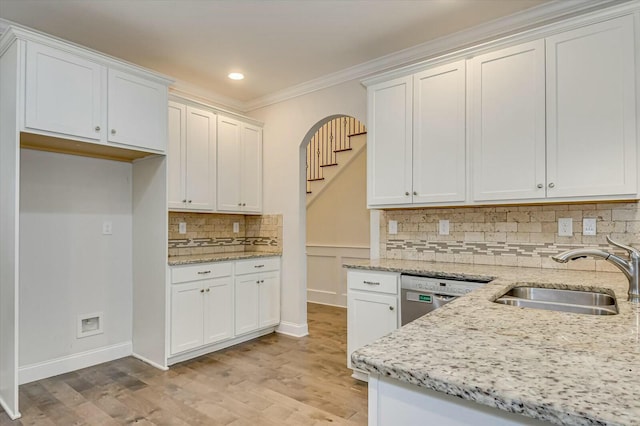 kitchen with sink, white cabinetry, crown molding, light stone counters, and dishwasher