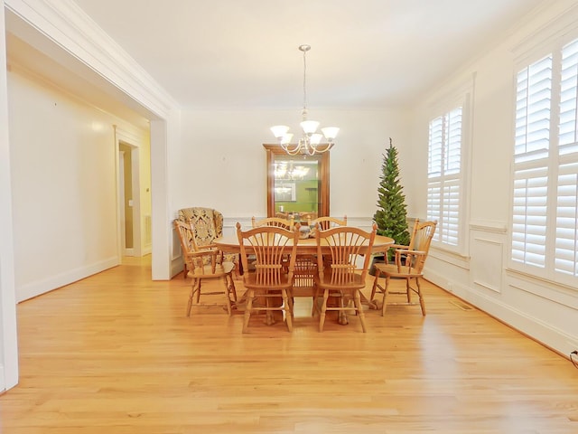 dining room featuring a notable chandelier, light wood-style flooring, and ornamental molding