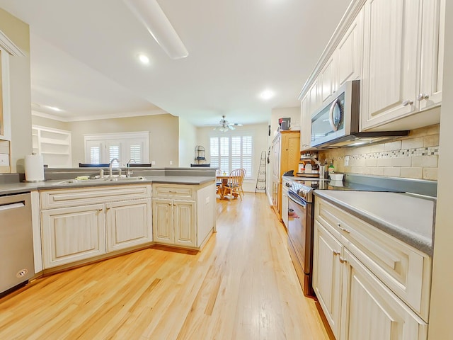 kitchen featuring light wood-style flooring, a sink, decorative backsplash, stainless steel appliances, and crown molding