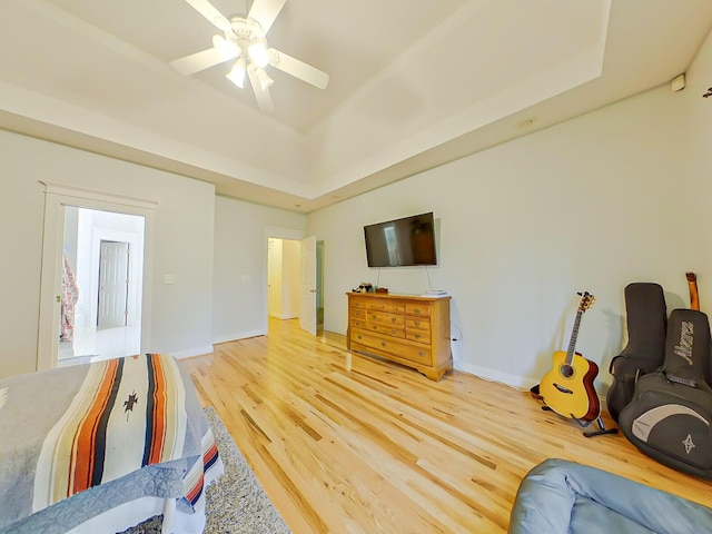 bedroom with baseboards, a ceiling fan, a tray ceiling, and wood finished floors