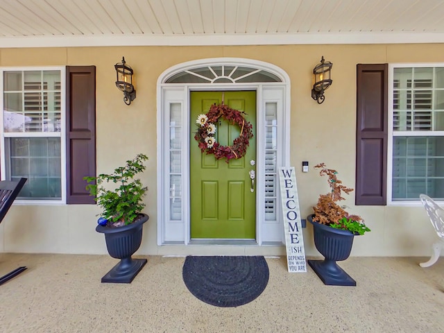 doorway to property with covered porch and stucco siding